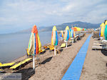 Parasols en ligbedden aan strand van Skala Kallonis